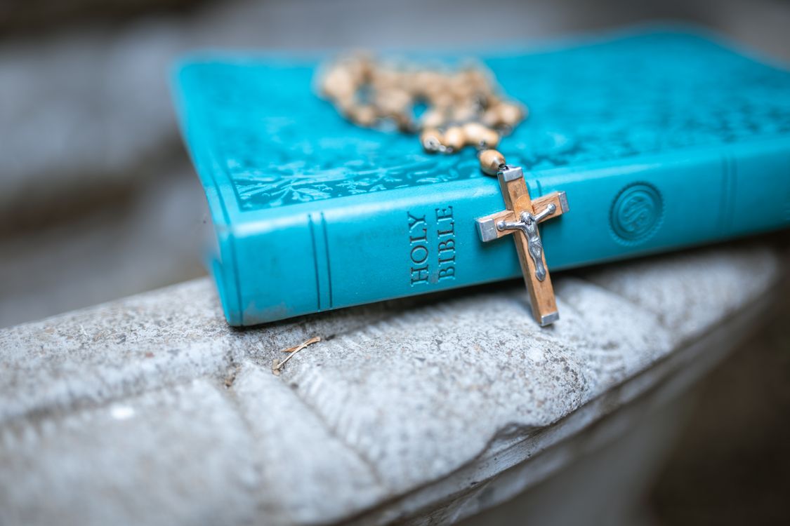 A crucifix and rosary resting on a Bible